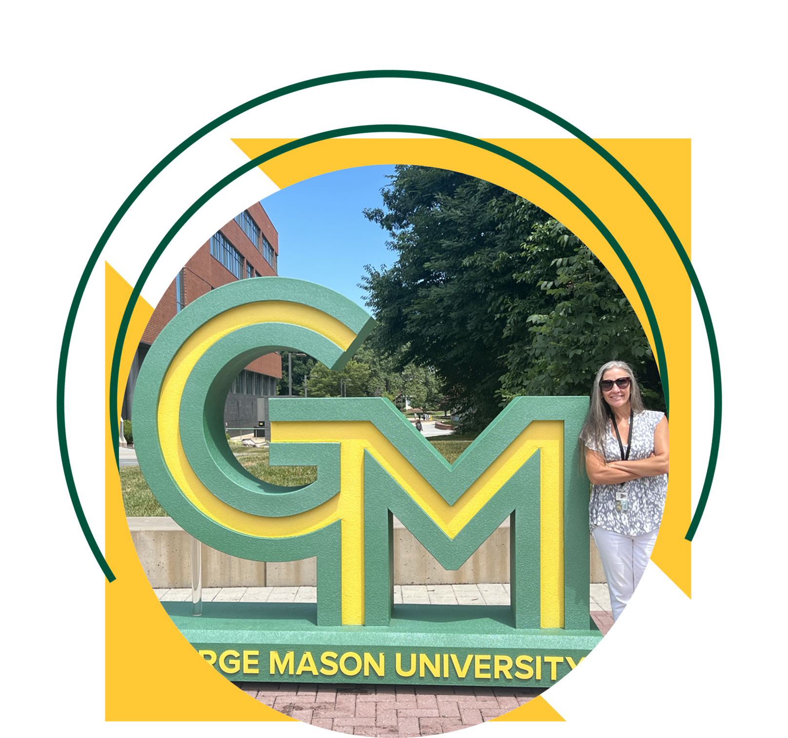 A woman stands beside a large green and gold “GM” George Mason University sign on a campus walkway, with trees and a brick building in the background. The image is framed within a circular design accented by yellow triangles and green curved graphic elements.