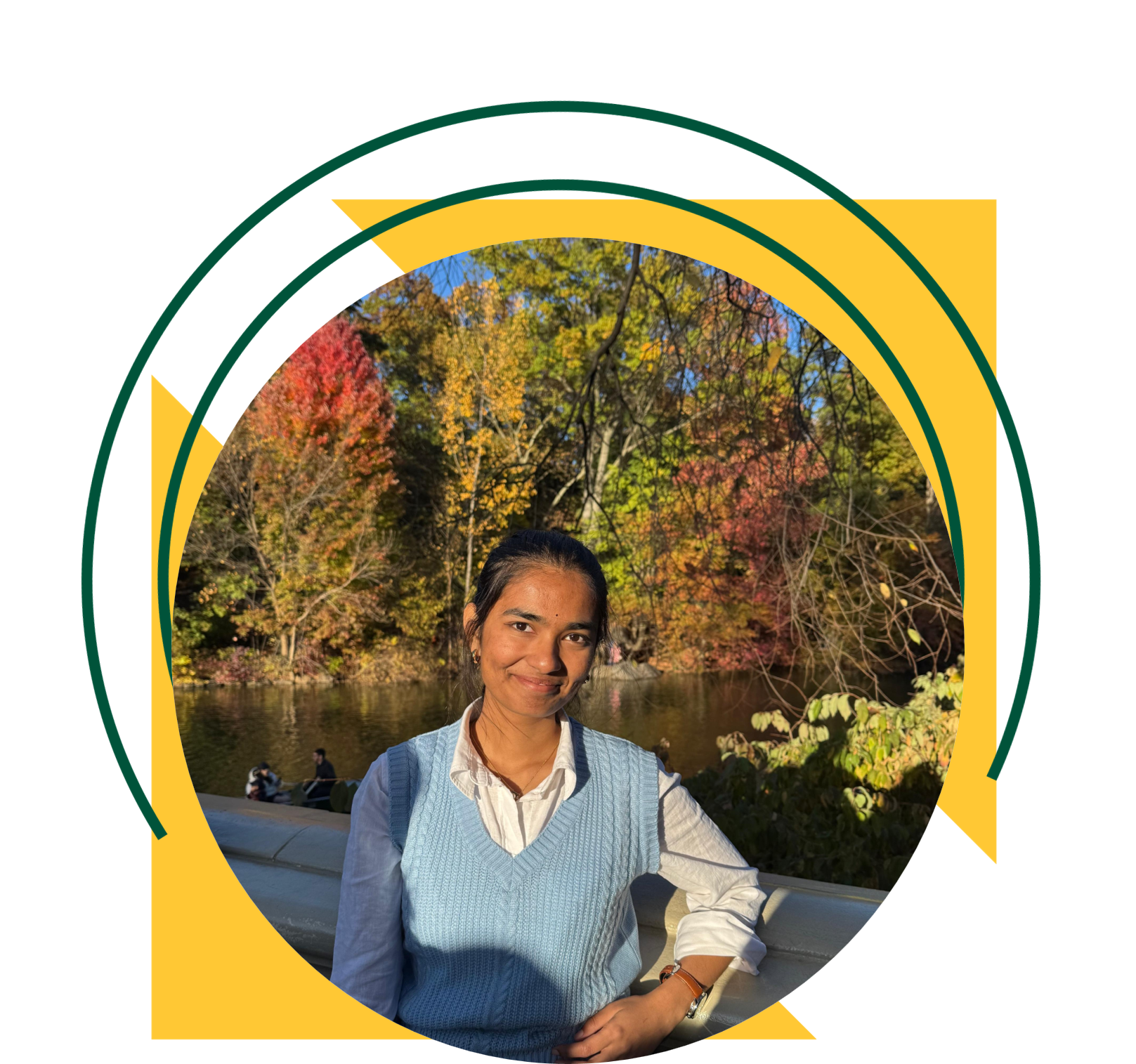 Woman standing beside a pond in a park, wearing a light blue sweater vest over a white shirt. Colorful autumn trees line the water in the background. The image is framed within a circular design accented by yellow triangles and green curved graphic elements.